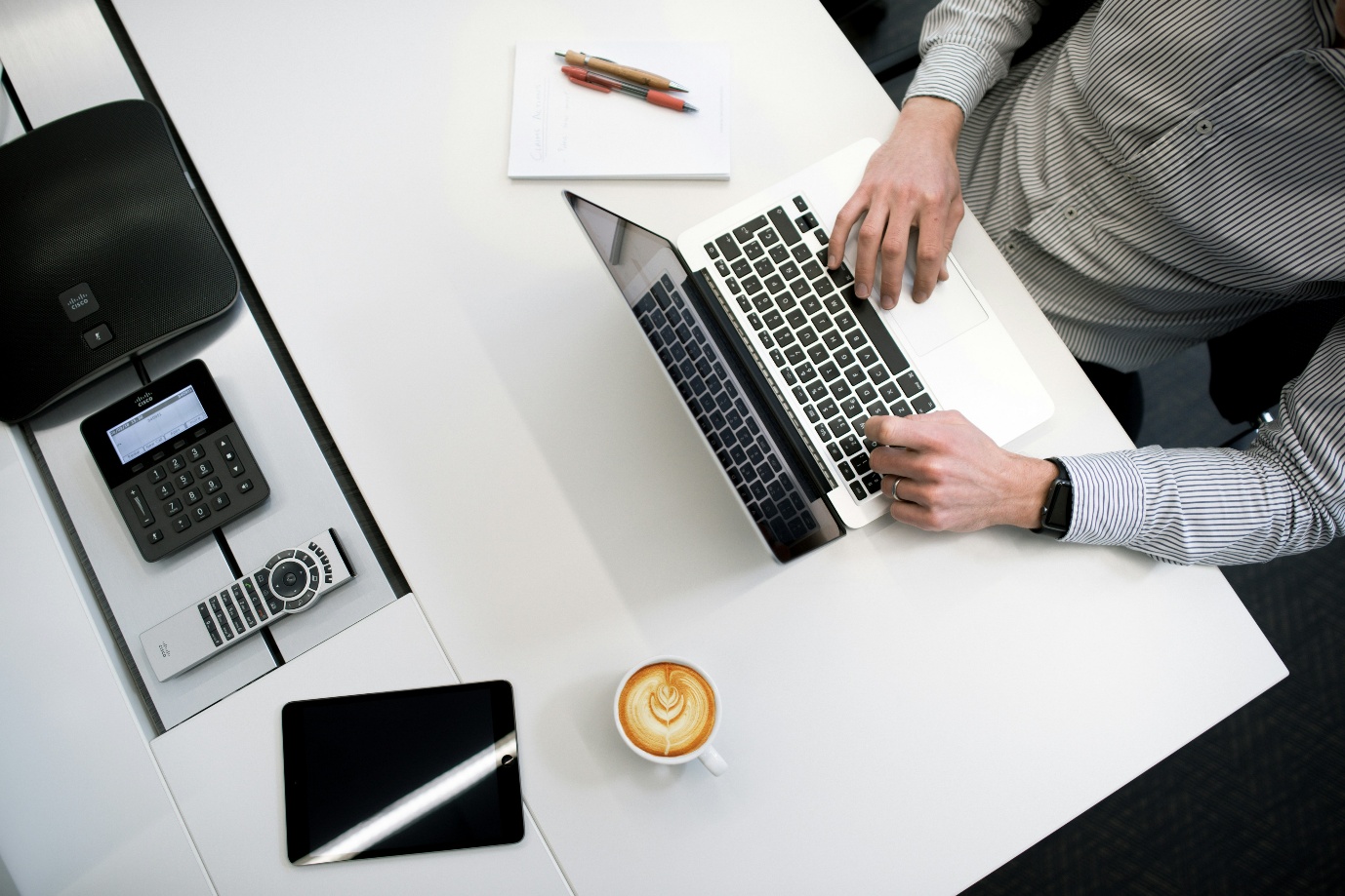 Person arbeitet am Laptop an einem Schreibtisch