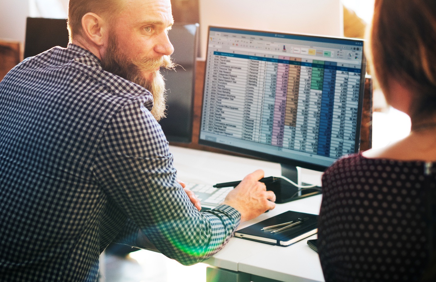 Zwei Kollegen besprechen eine Excel-Tabelle am Bildschirm